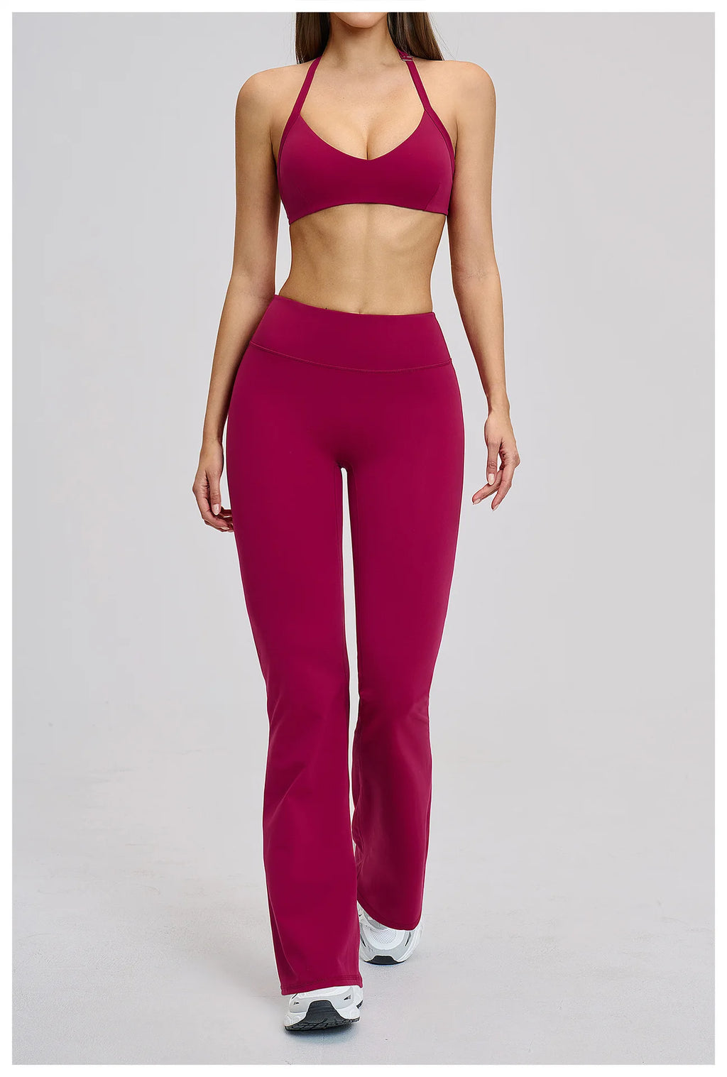 Person wearing a maroon sports bra and leggings set on a light gray background