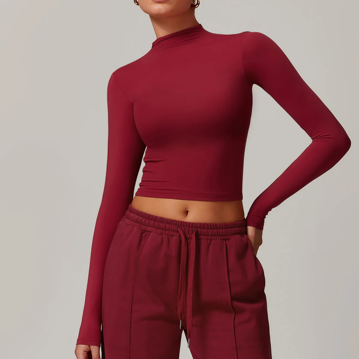 Person wearing a maroon long-sleeve top and pants against a neutral background