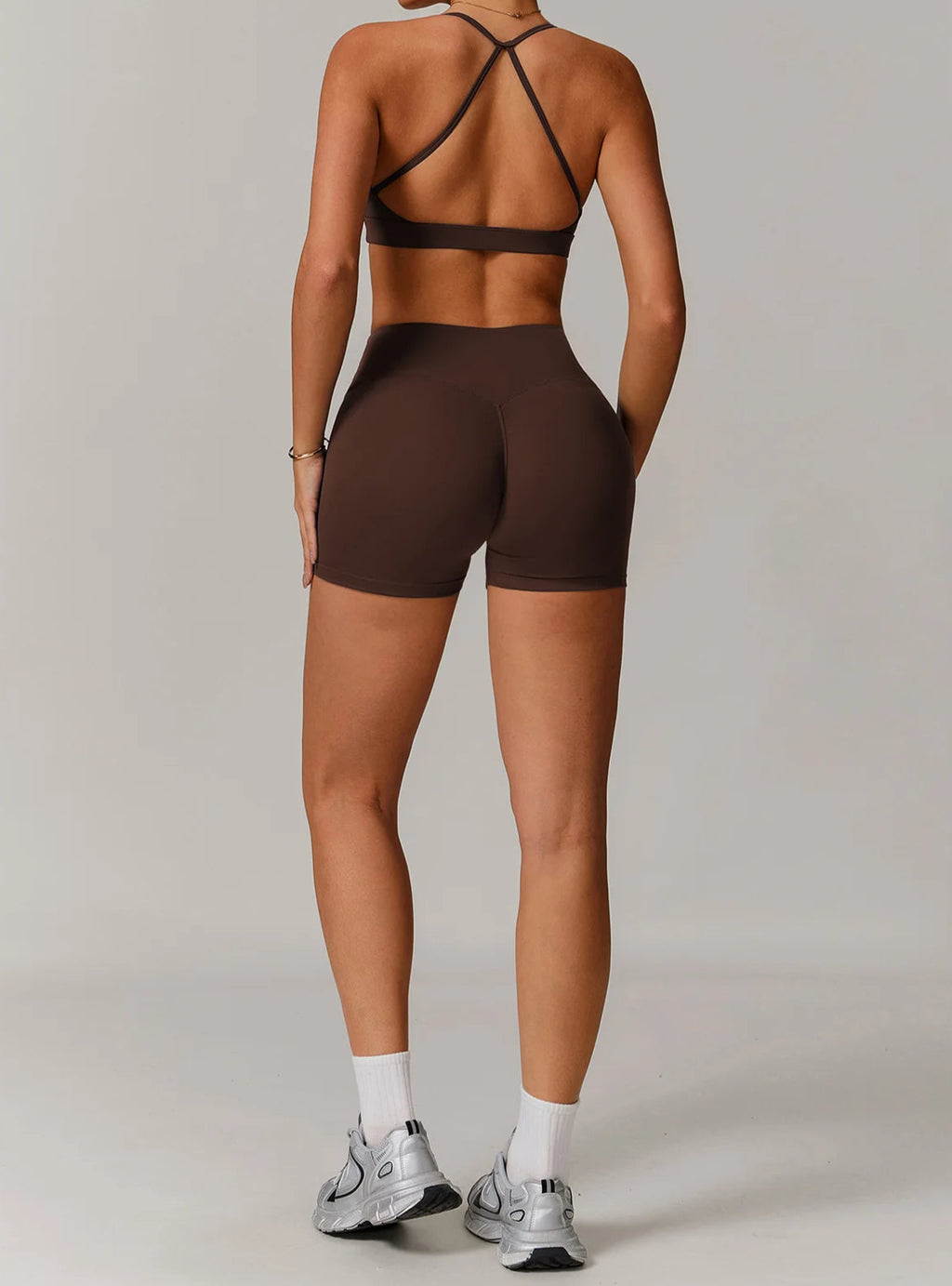 Person wearing a brown sports bra and shorts set on a plain background