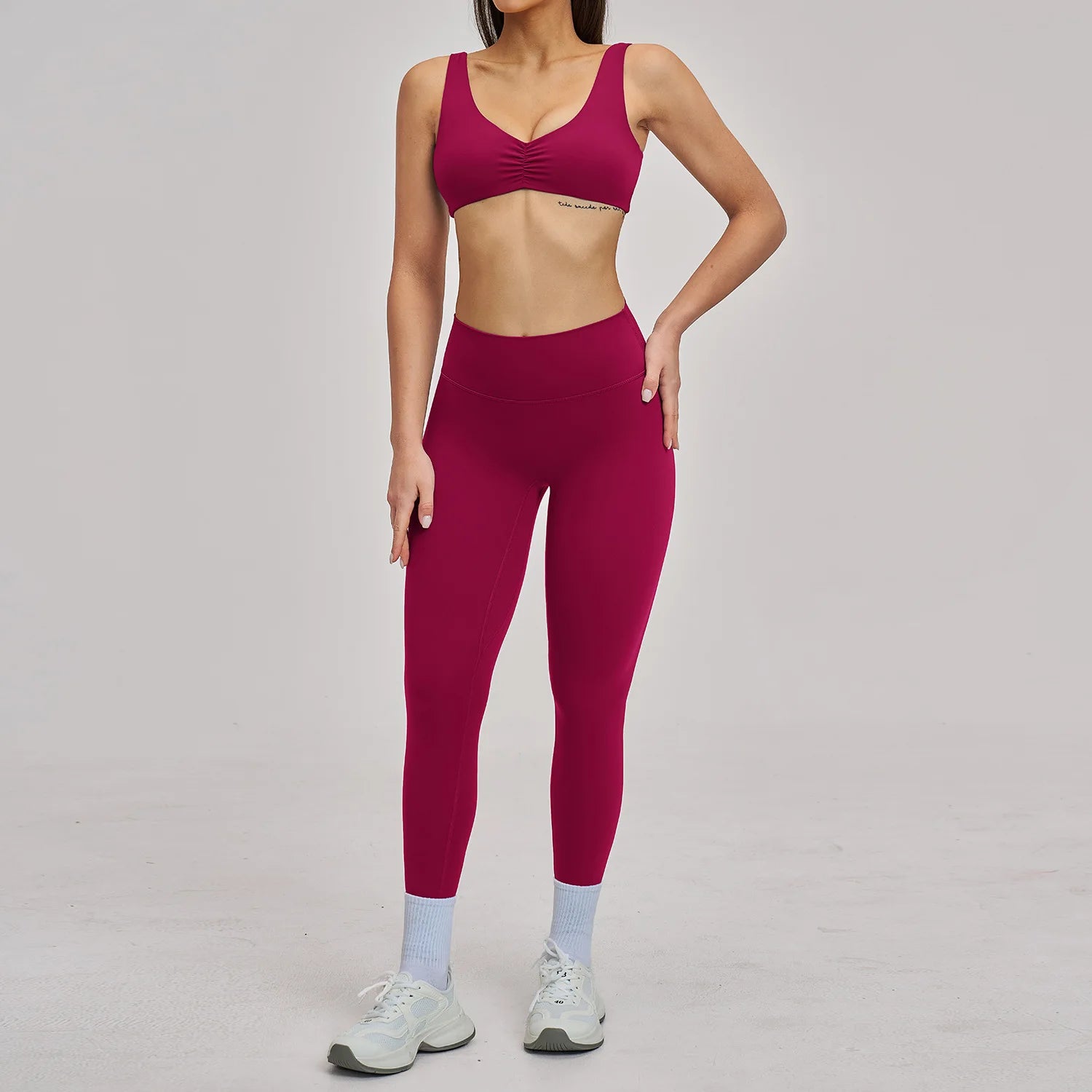 Person wearing a maroon sports bra and leggings set on a gray background
