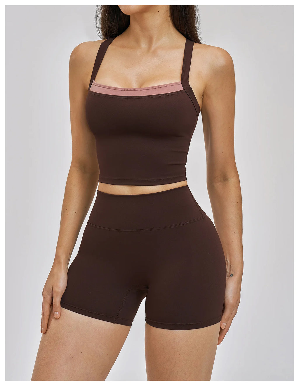Woman wearing a brown sports bra and shorts set on a plain background