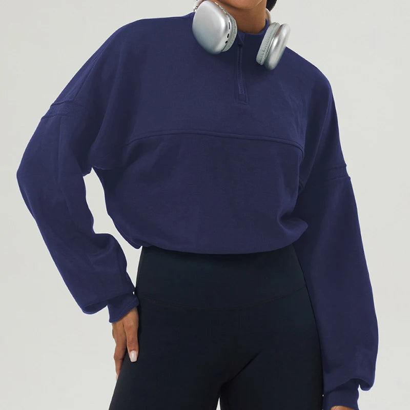 Person wearing a navy blue sweatshirt with a pocket on a plain background