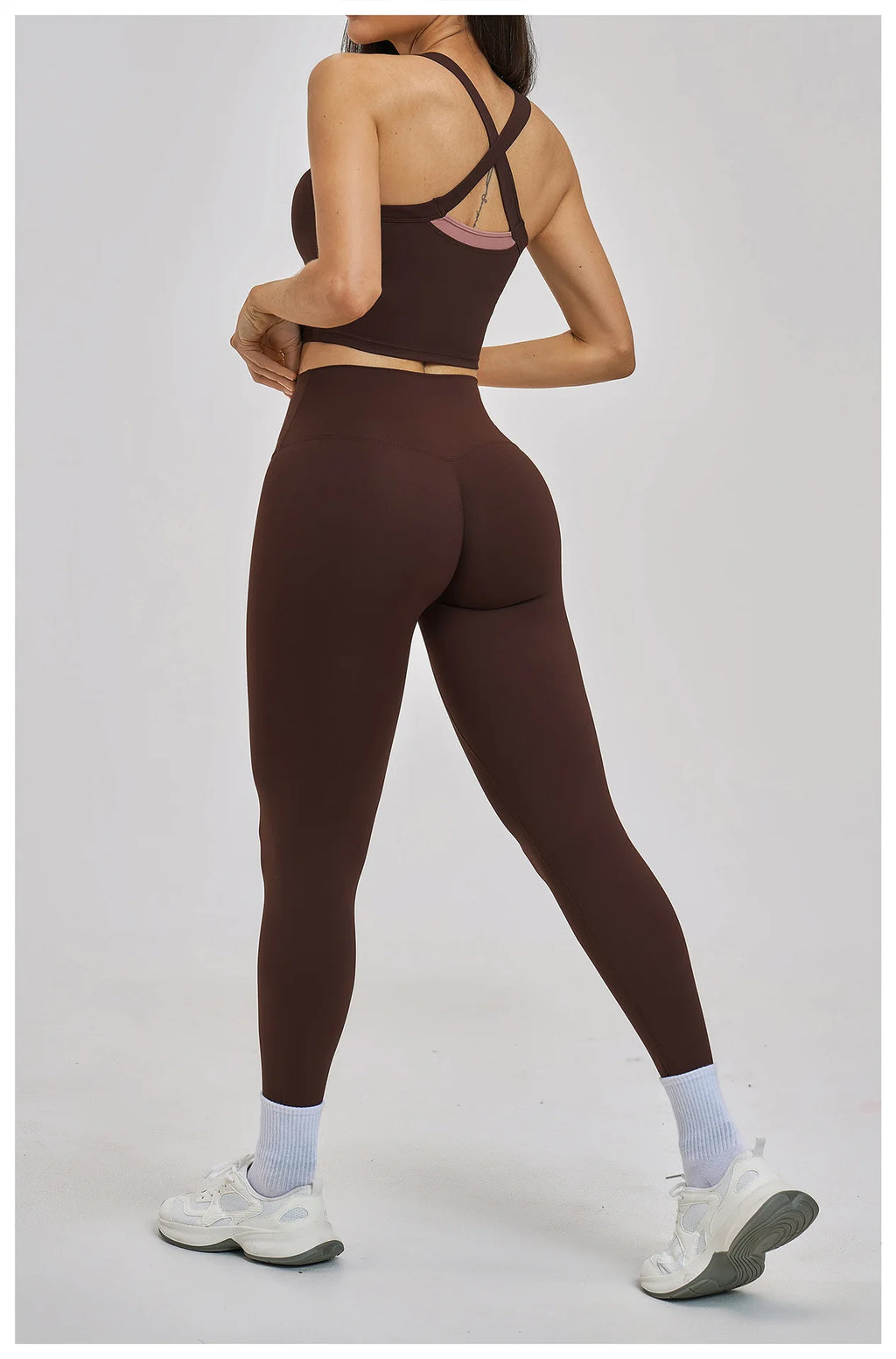 Person wearing a brown sports bra and leggings set on a white background
