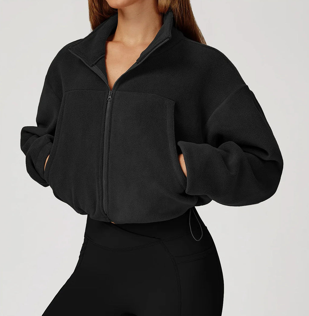 Black plush jacket worn by a woman on a light gray background