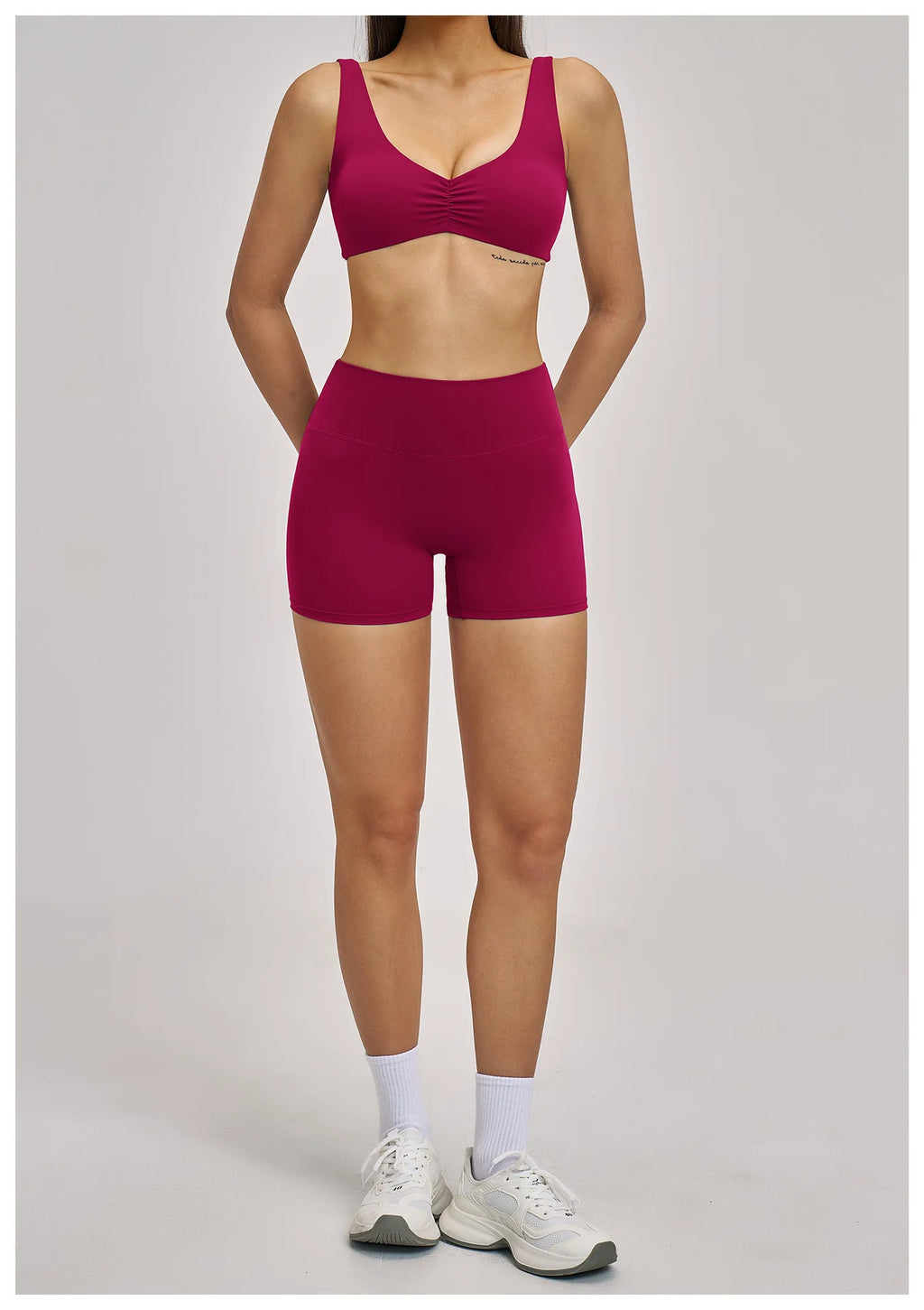 Person wearing a pink sports bra and shorts set on a gray background