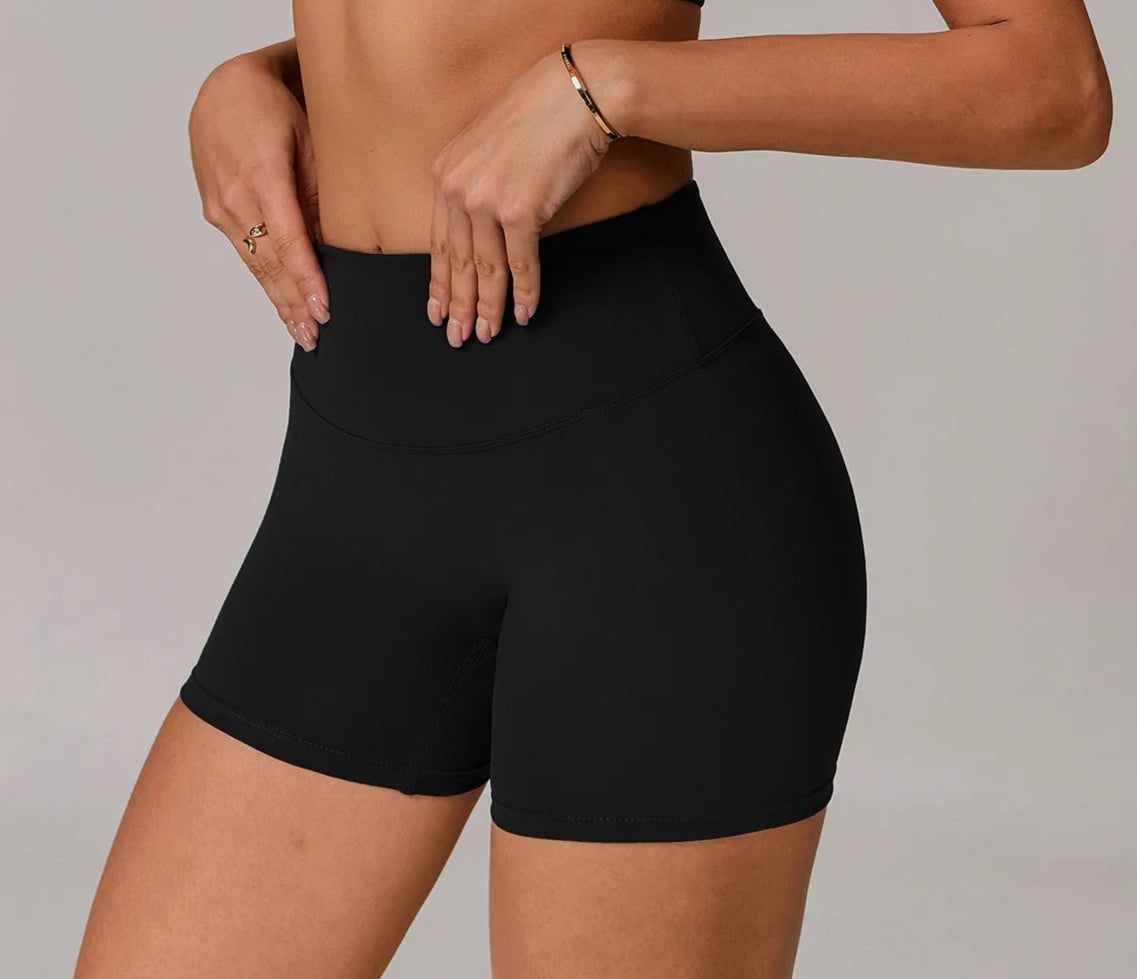 Person wearing black high-waisted shorts on a plain background