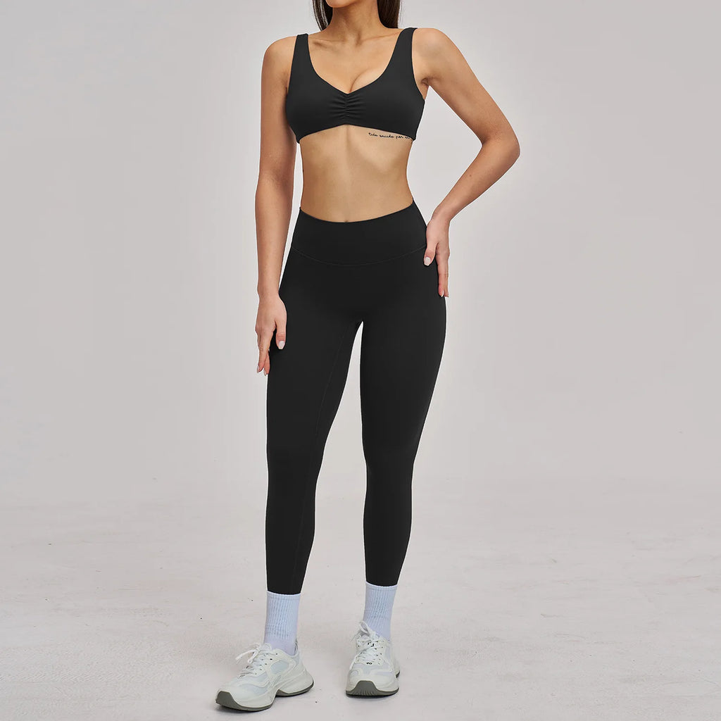 Person wearing a black sports bra and leggings set on a plain background