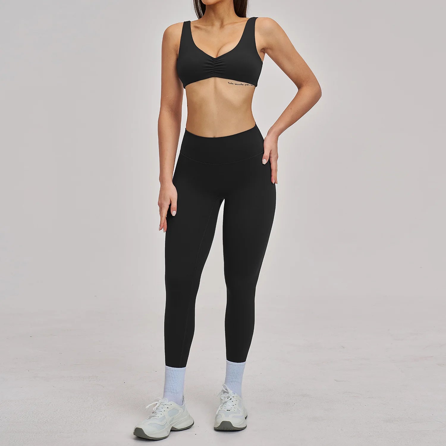 Person wearing a black sports bra and leggings set on a plain background