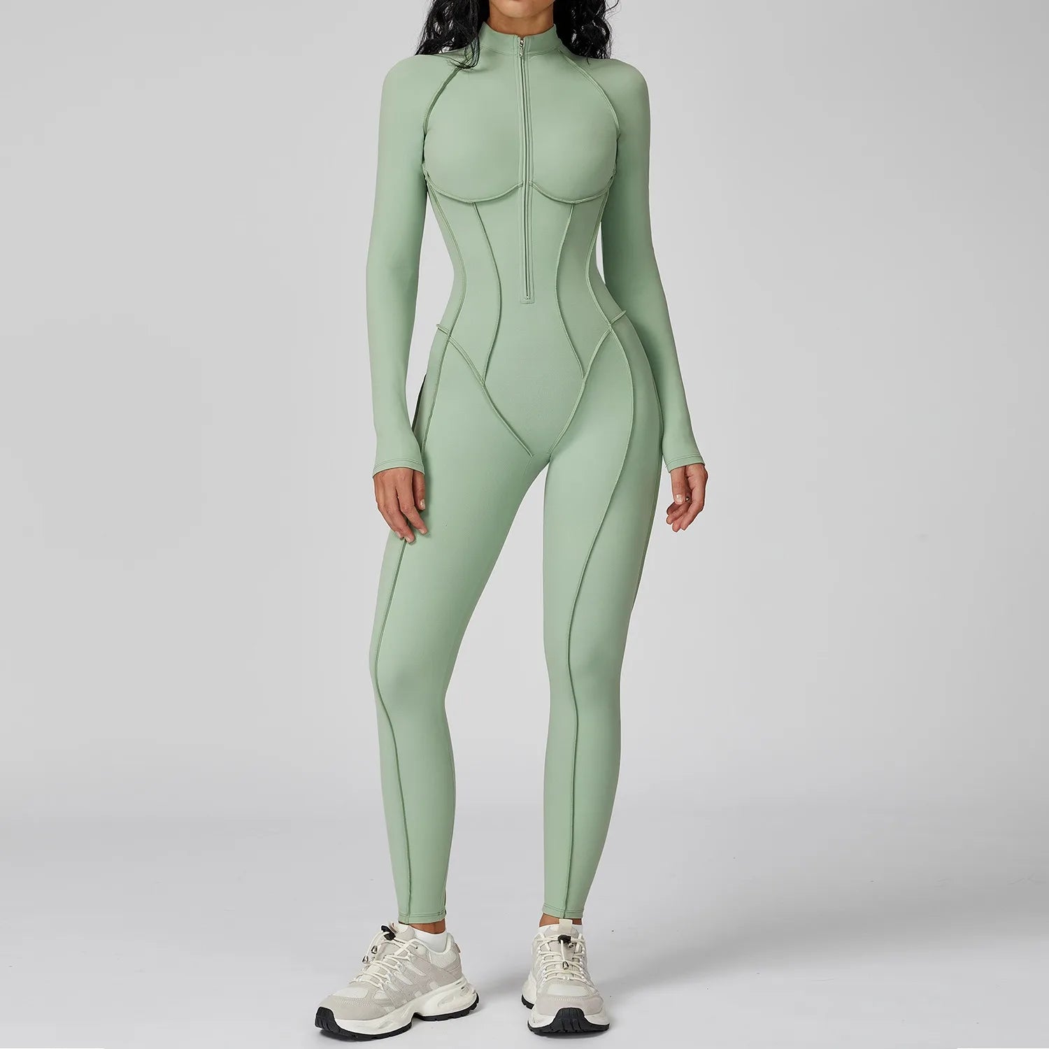 Woman wearing a pastel green sports longsleeve bodysuit on a plain background