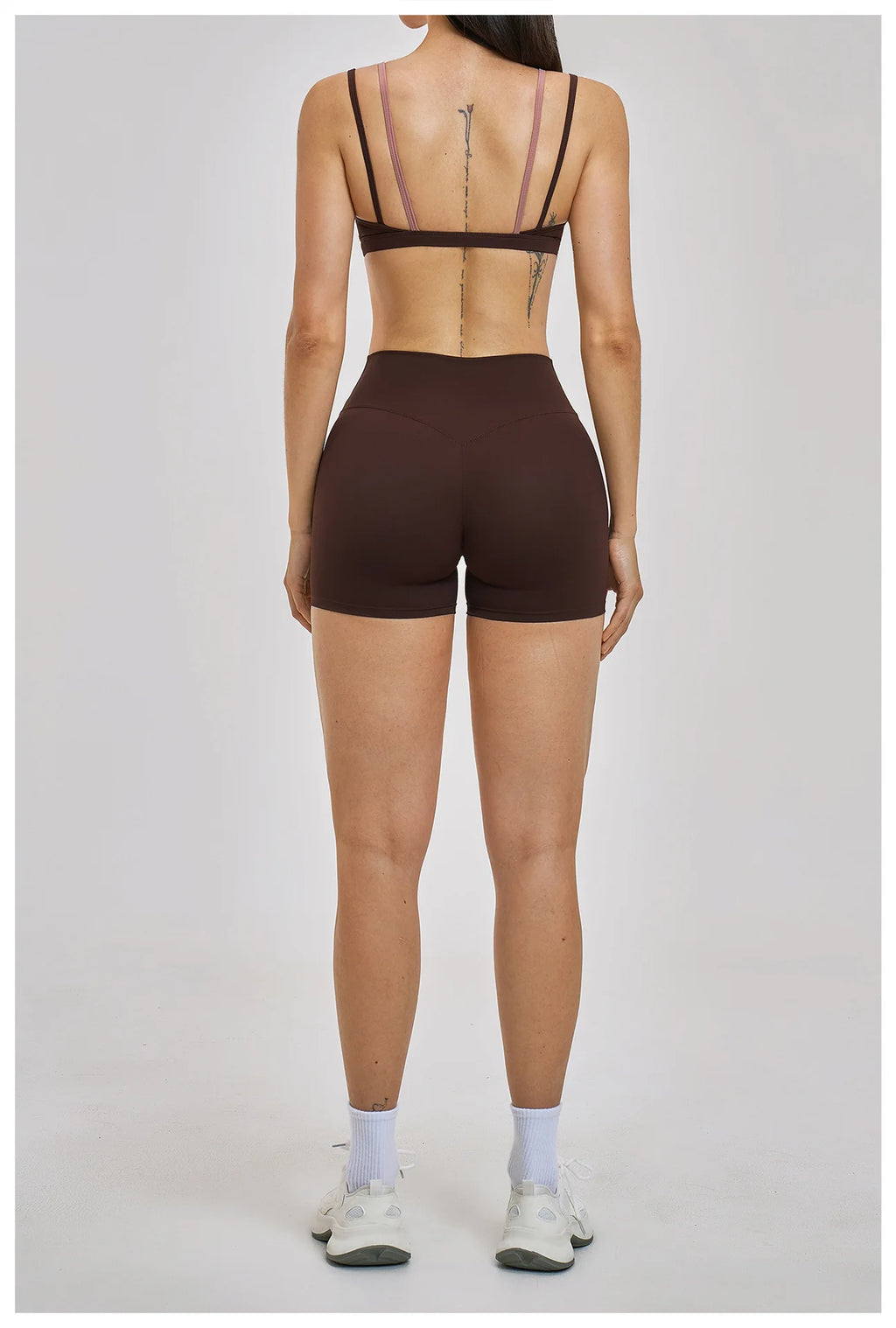 Person wearing a brown bra and shorts set on a plain background
