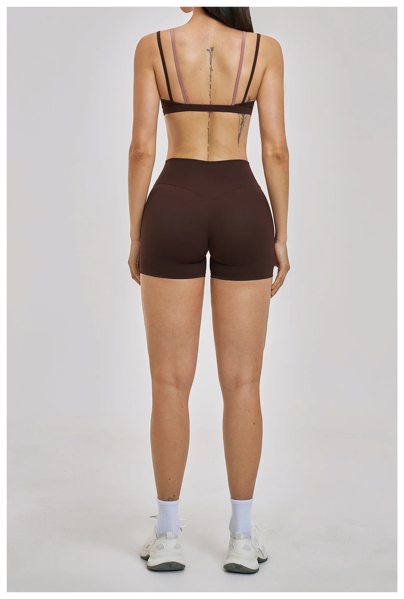 Person wearing a brown bra and shorts set on a plain background
