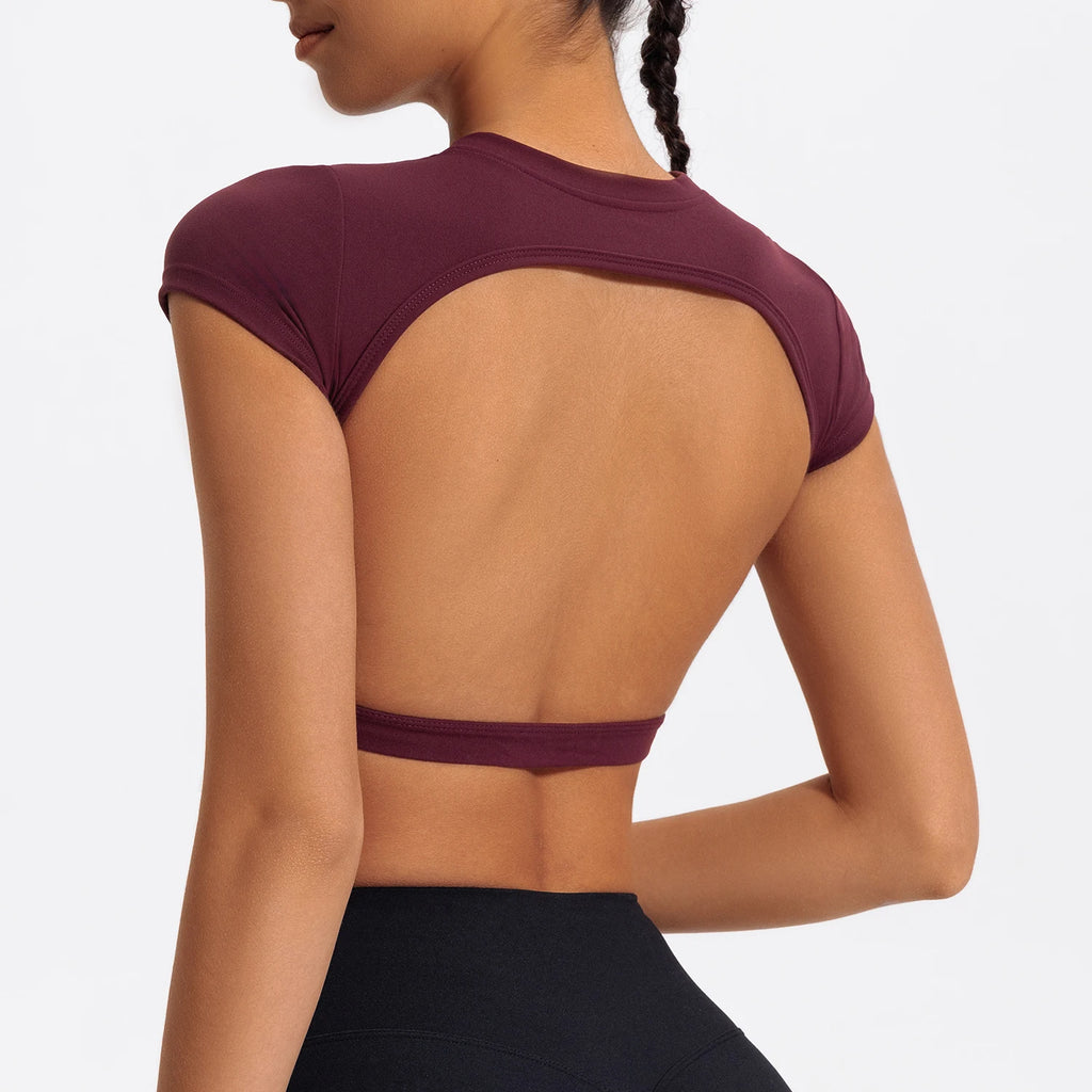 Woman wearing a maroon sports bra and black leggings on a light gray background