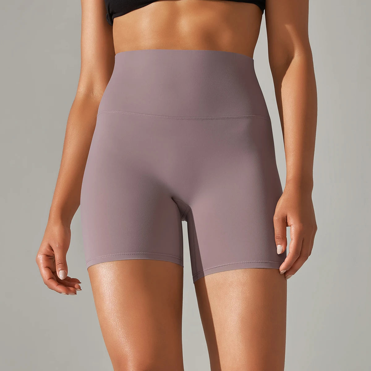 Person wearing a pair of purple athletic shorts on a neutral background