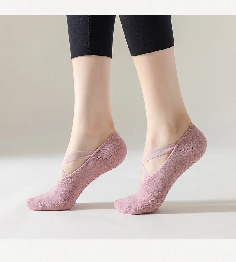 Pink socks worn with black leggings on a plain background
