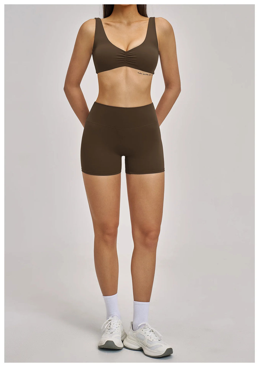 Person wearing a brown sports bra and shorts set on a gray background