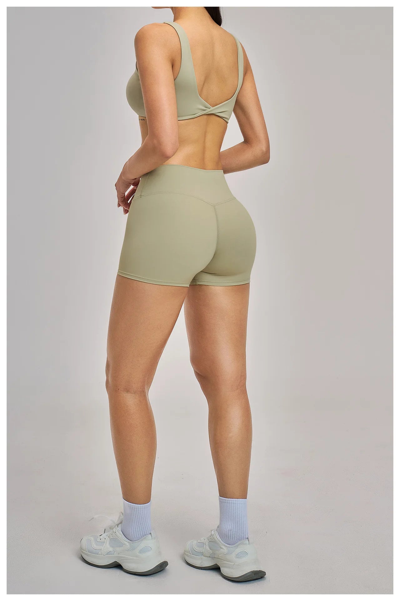 Person wearing a green sports bra and shorts set on a plain background