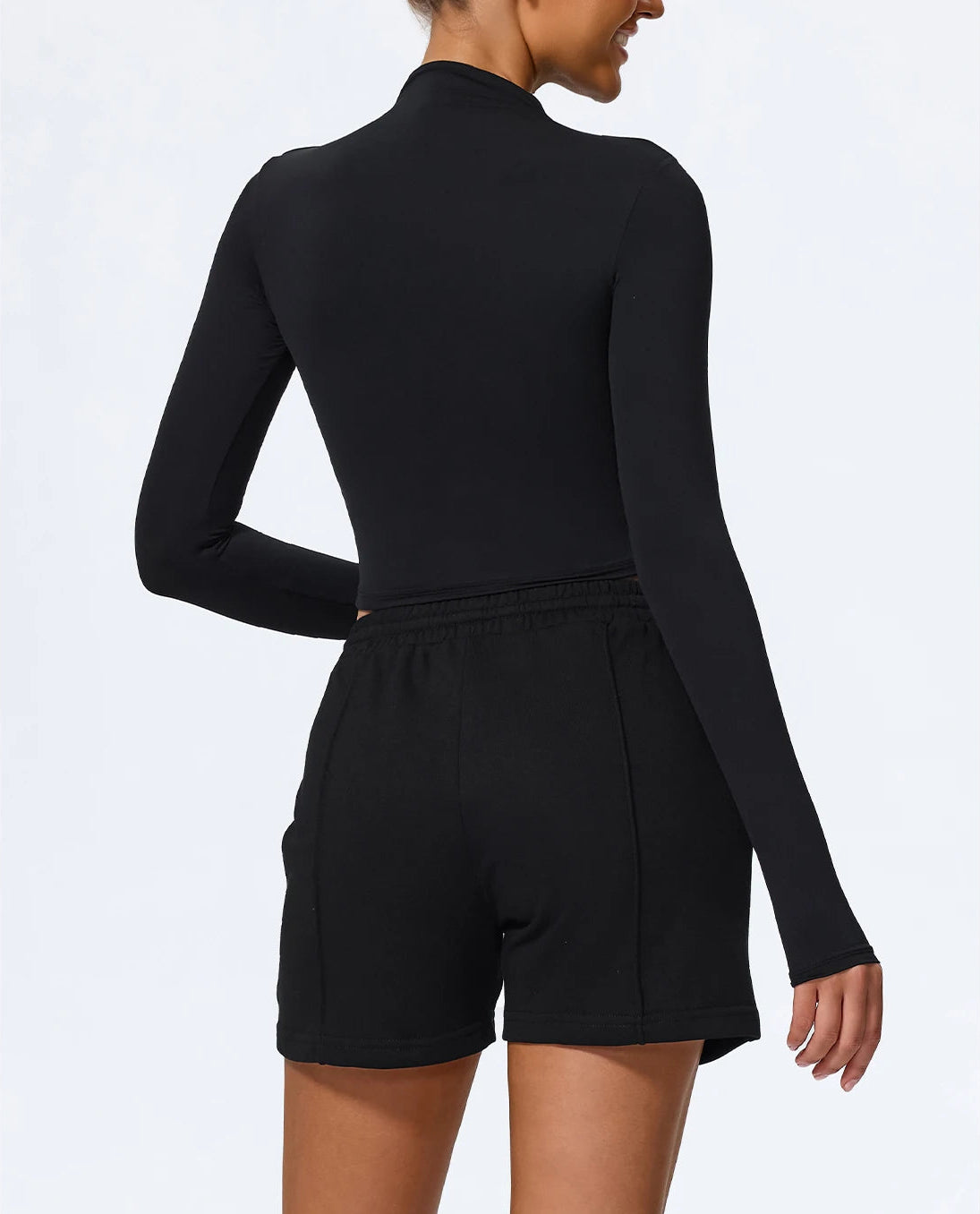 Black long-sleeve romper worn by a person on a white background