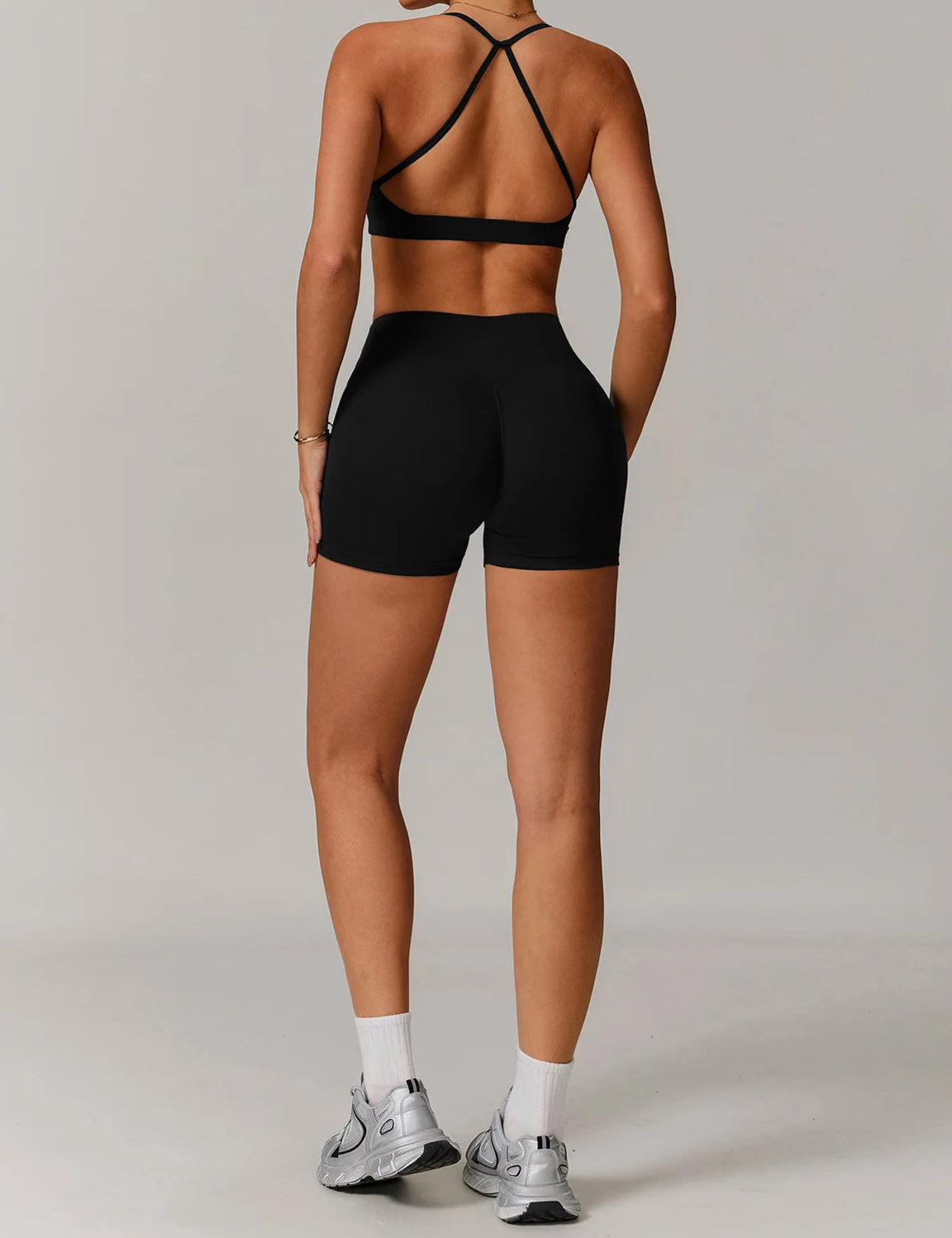 Person wearing black athletic top and shorts on a plain background
