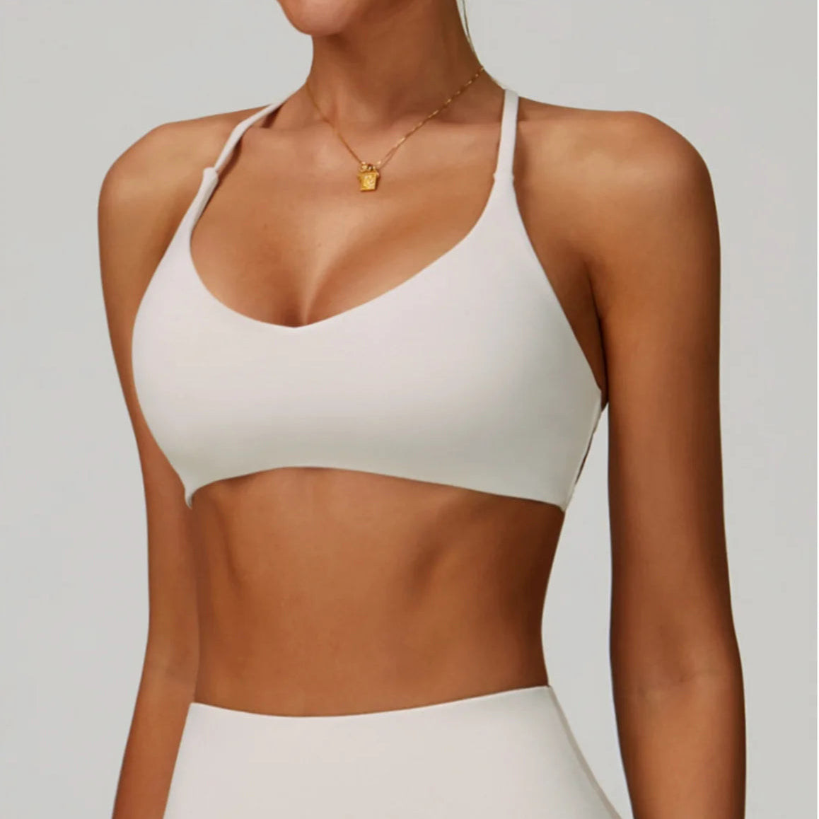 Person wearing a white sports bra and leggings on a plain background
