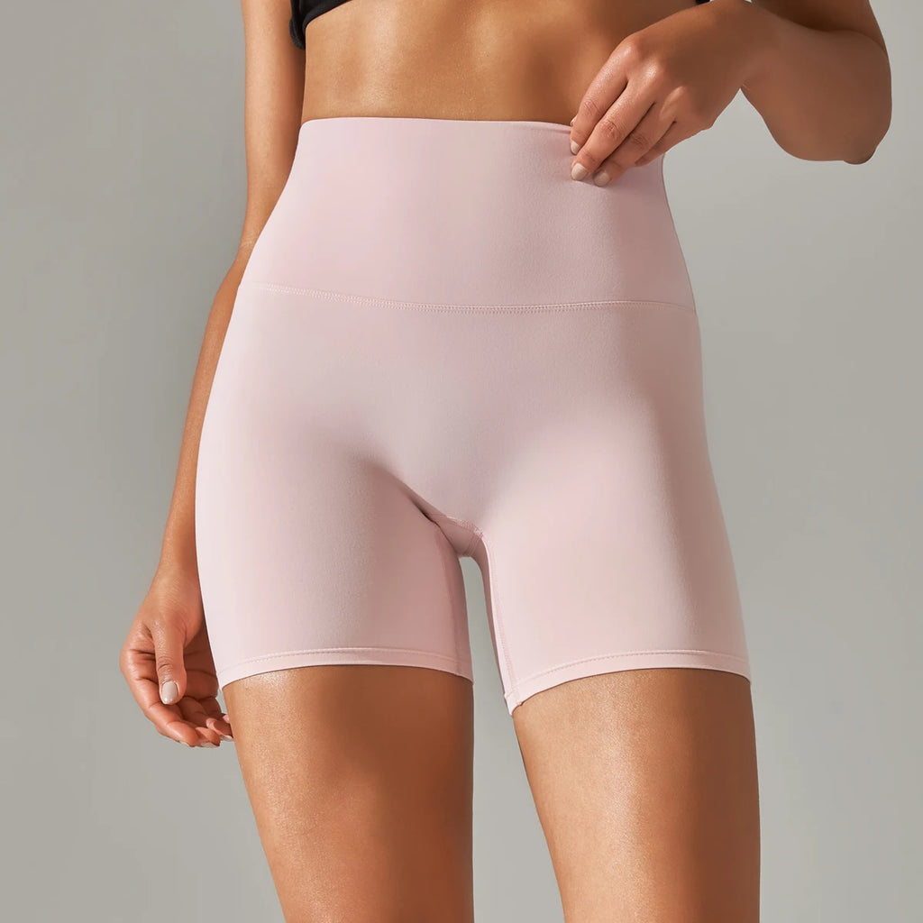 Person wearing light pink high-waisted shorts on a gray background