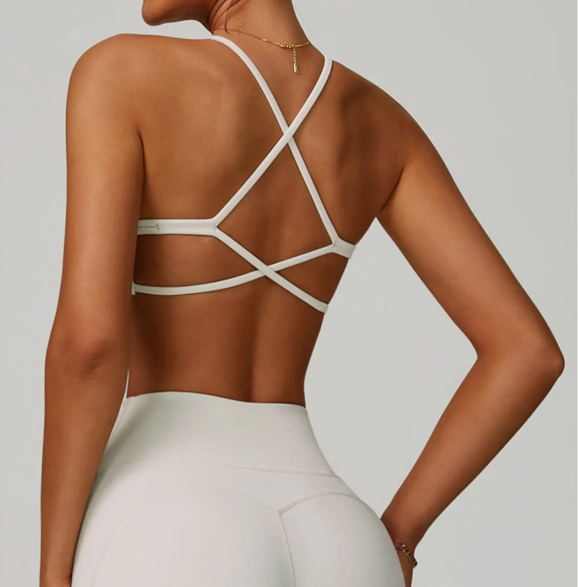Person wearing a strappy white top with a plain background