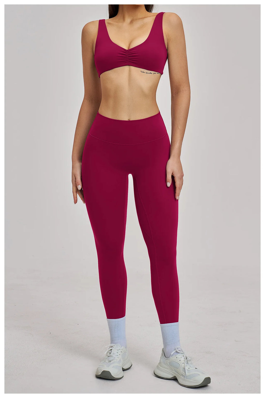 Person wearing a maroon sports bra and leggings set on a plain background