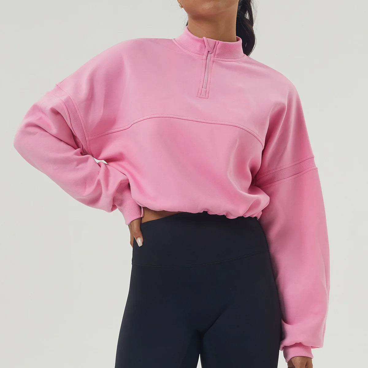 Person wearing a pink sweatshirt and black pants on a white background