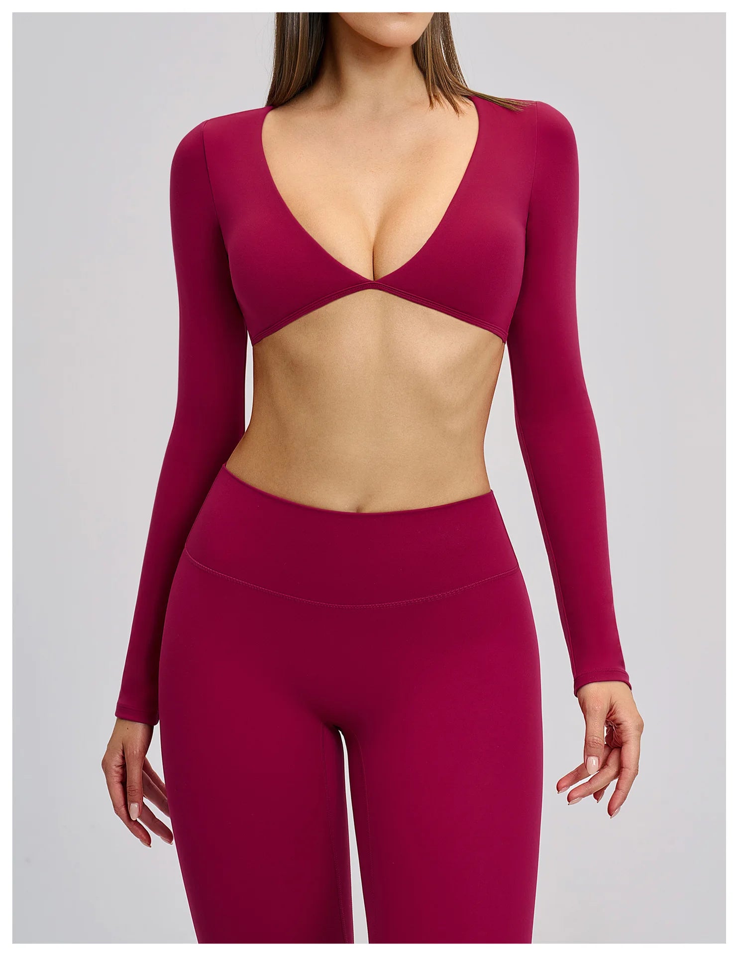 Person wearing a burgundy long-sleeve top and leggings on a plain background