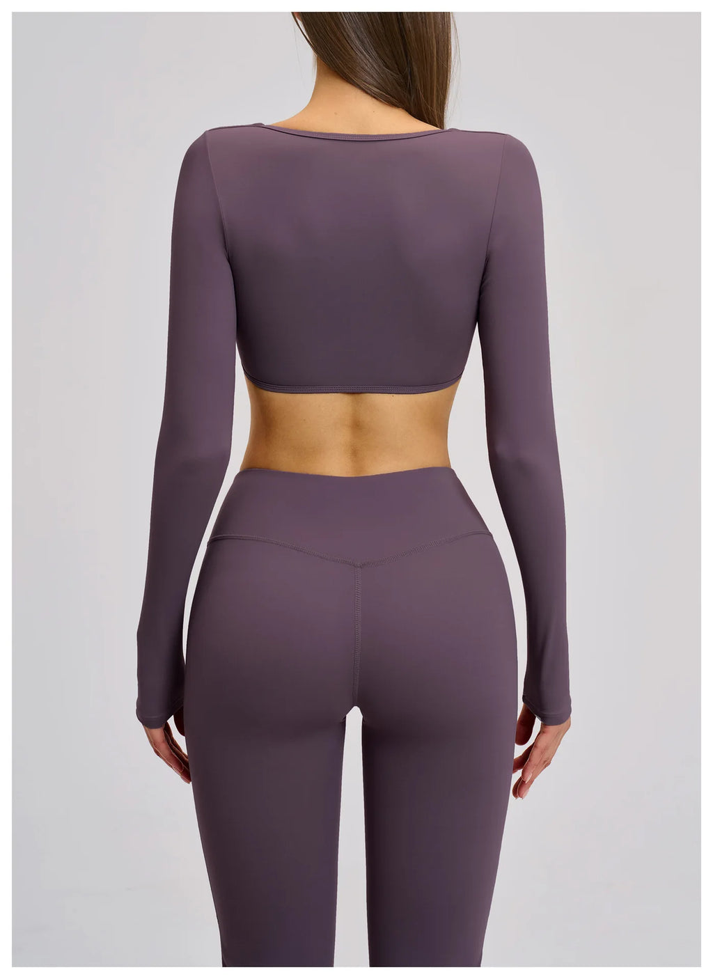 Purple athletic outfit with long-sleeve top and leggings on a plain background