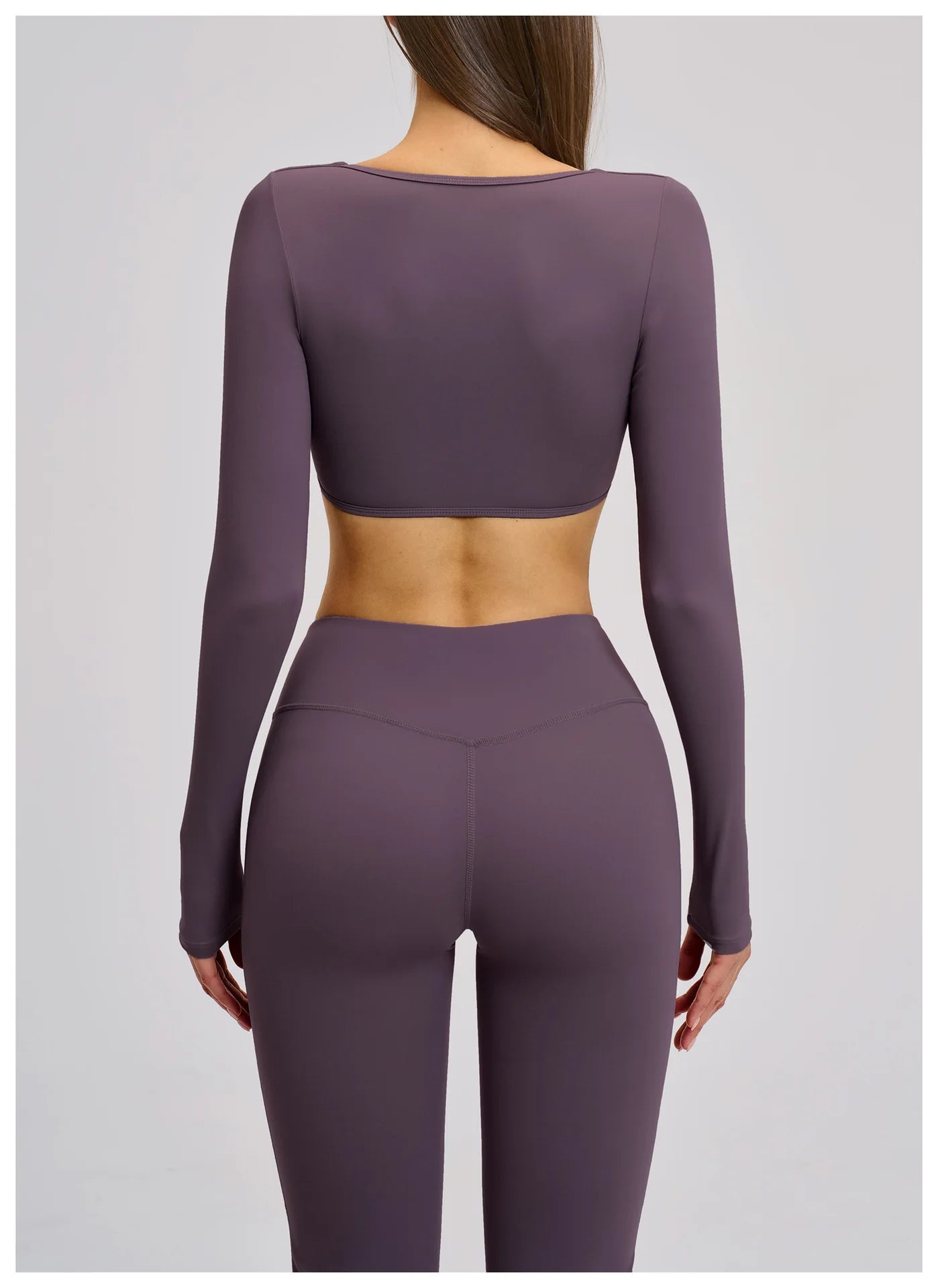 Purple athletic outfit with long-sleeve top and leggings on a plain background