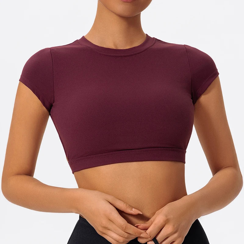 Person wearing a maroon crop top against a neutral background
