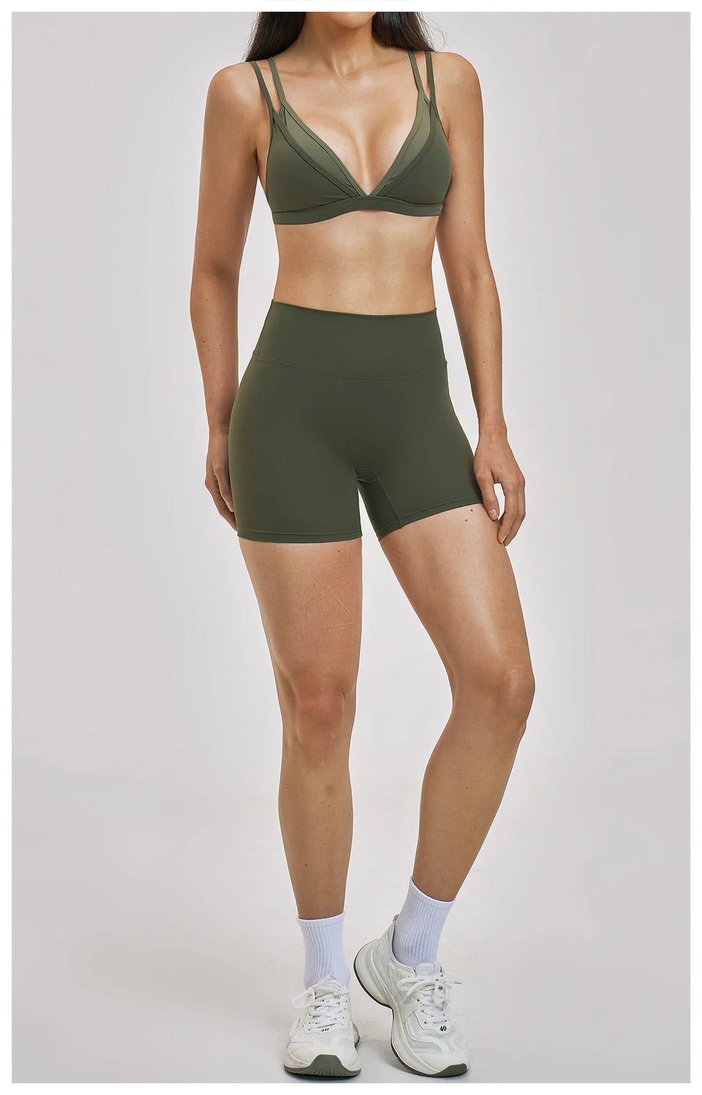Person wearing a green sports bra and shorts set on a plain background